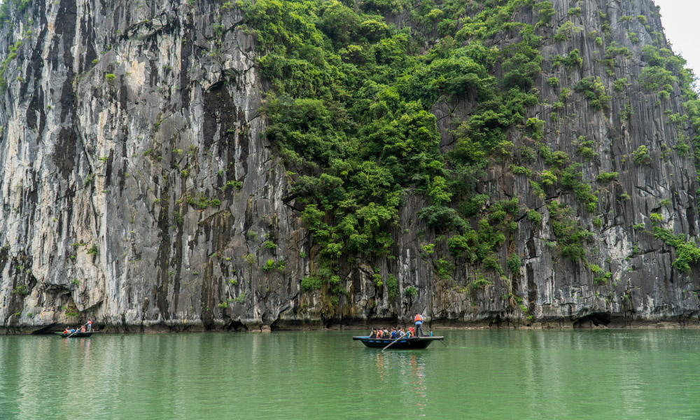 a bamboo boat going in the middle of halong bay