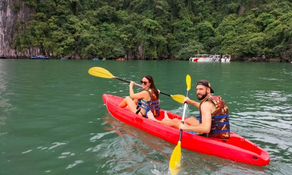 A red kayak with a couple sailing in the middle of the bay.