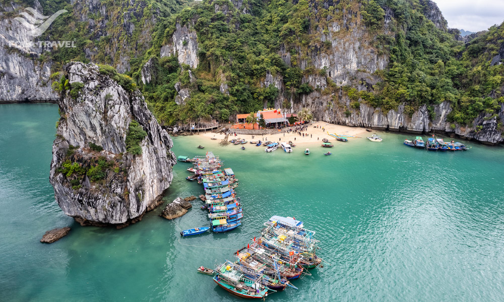 A small temple on a beach surrounded by mountains and the sea.