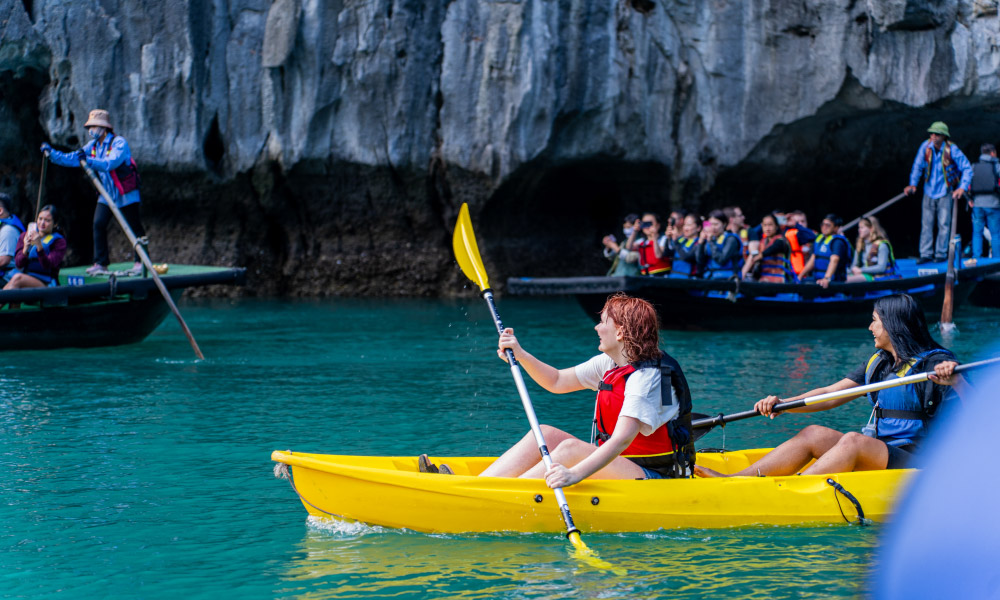 people kaayking and going on bamboo boats in halong bay