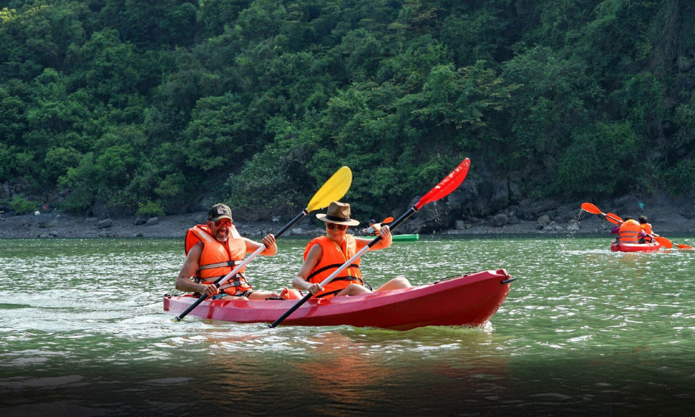 two people kayaking in halong bay wearing orange life jackets