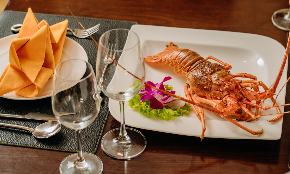 Table with a plate of lobster and two wine glasses.