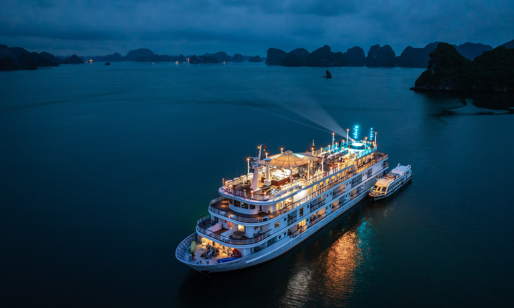 Night view of Halong Bay with Ambassador Signature Cruise lighting up.