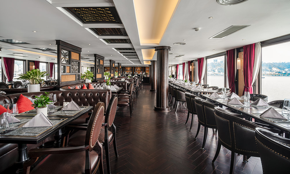 A luxury restaurant with two rows of tables and windows on the right.