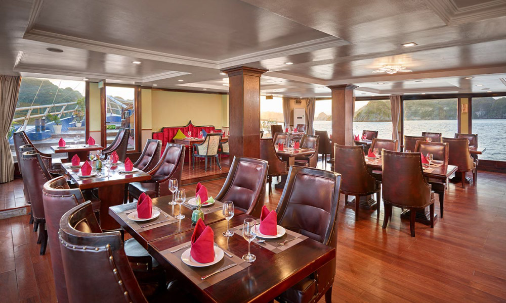 A restaurant with brown tone, leather chairs and red napkins on white plates.