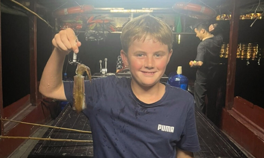 A boy holding a squid smiling.