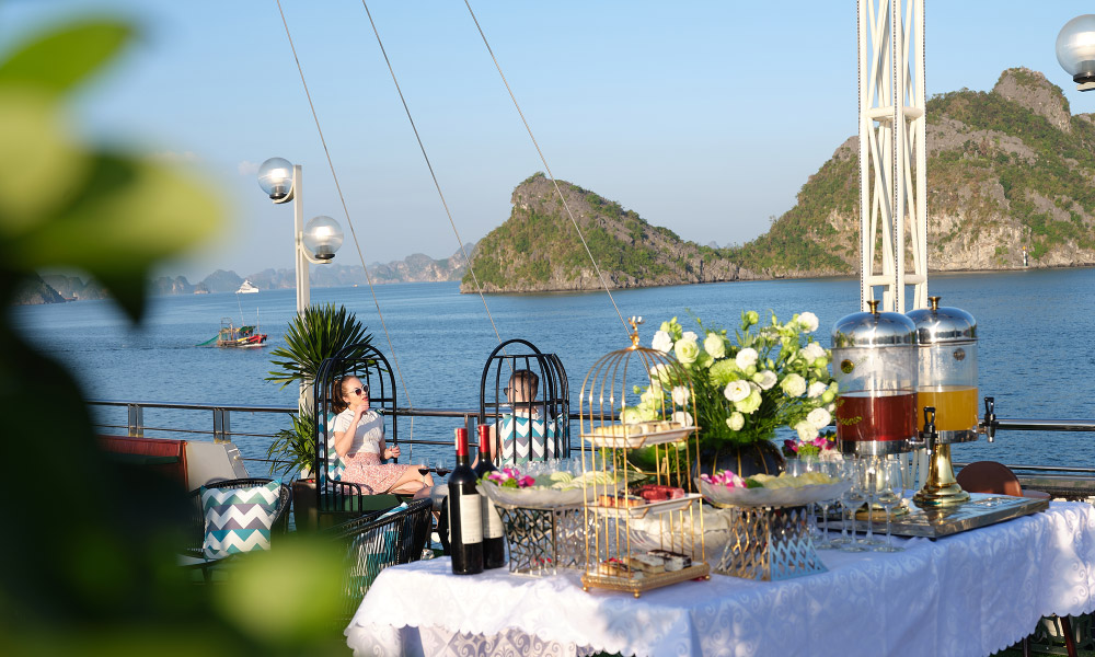 A desk full of fruits and drinks with flower decoration.