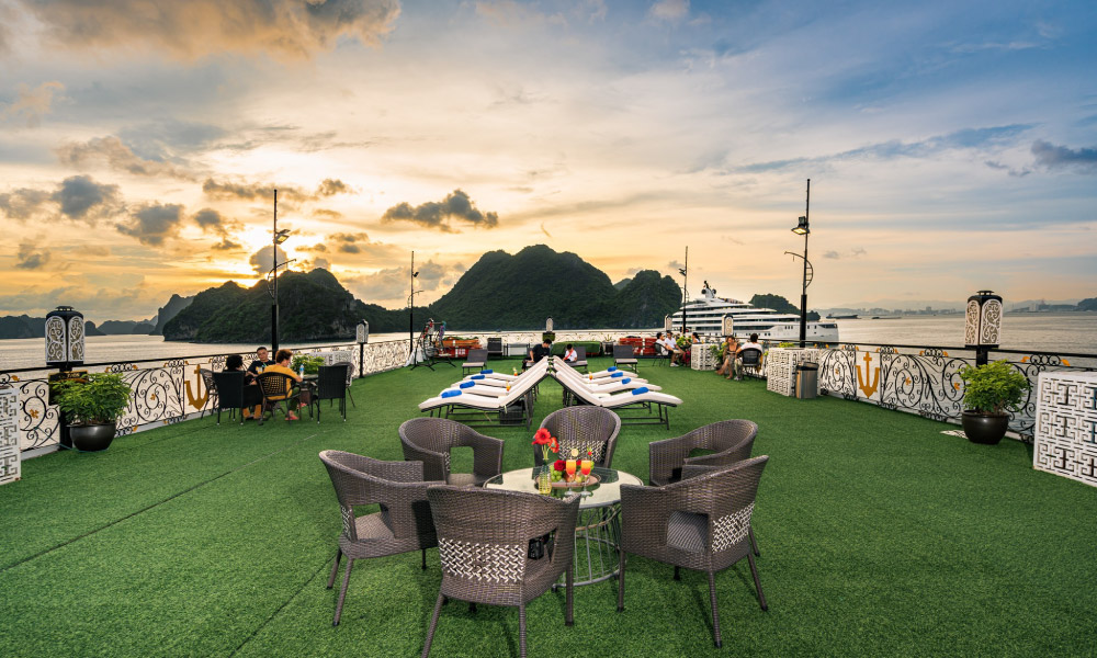 The deck of Aquamarine Cruise during sunset with tables and Halong View