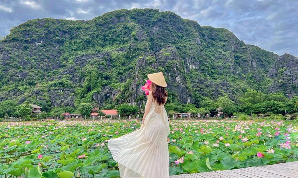 A girl in the middle of Tam Coc lotus lake and mountains.