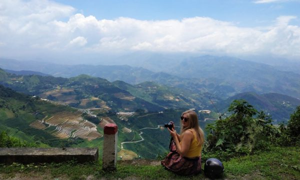 A girl sitting with view of Ha Giang behind.