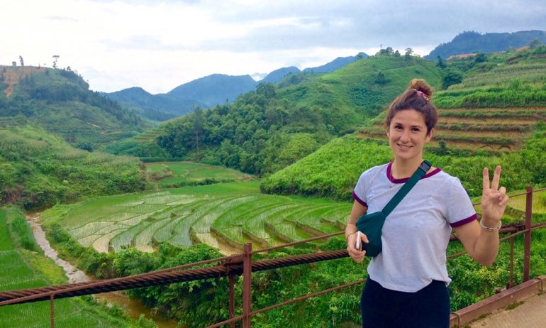 A girl smiling in front of a rice field in Ha Giang.