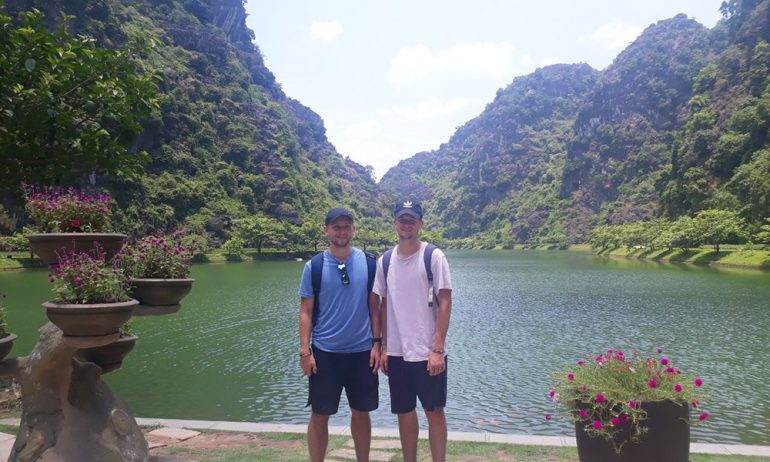 Two men standing in the middle of Tam Coc view.