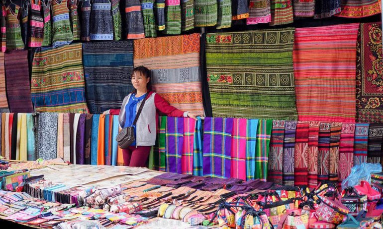 A woman standing in the middle of a textiles and fabrics shop.