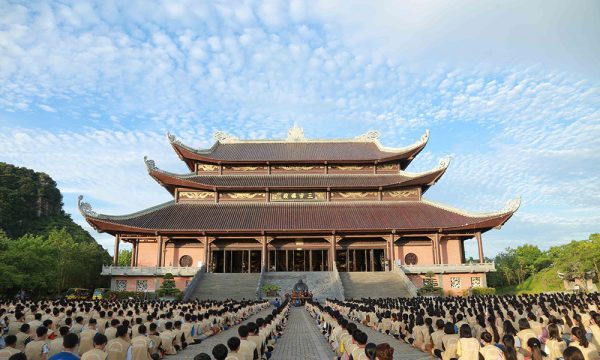 Front view of Bai Dinh Pagoda with many students sitting in front.