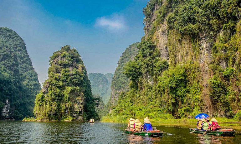 Two boats on the right sailing in Trang An among the mountains.