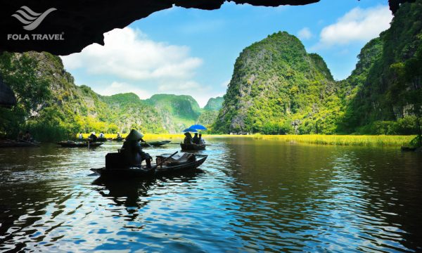 Some boats going through a cave looking out to view of mountains in Tam Coc.