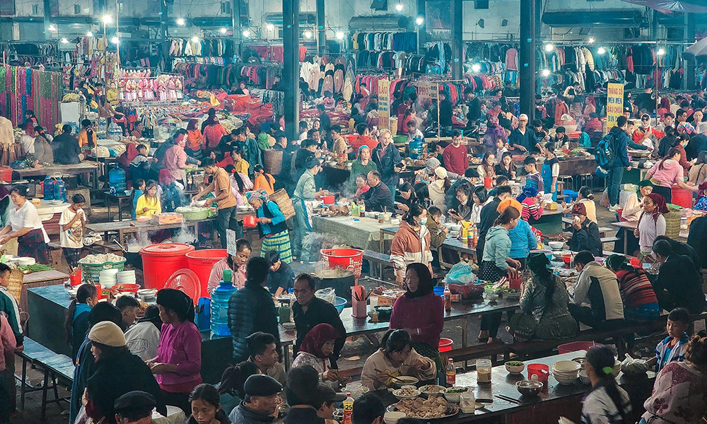 A market in Ha Giang full of people eating and walking.