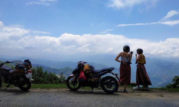 Two girls standing on Ha Giang mountains with view of the sky.