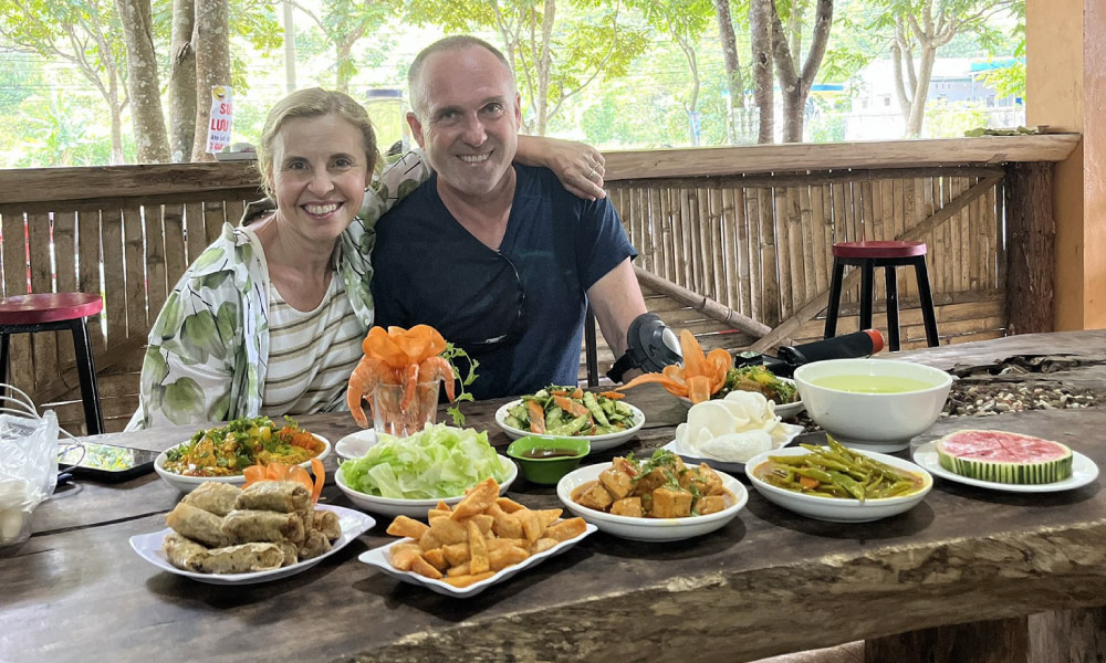 A couple in front of a table with many food.