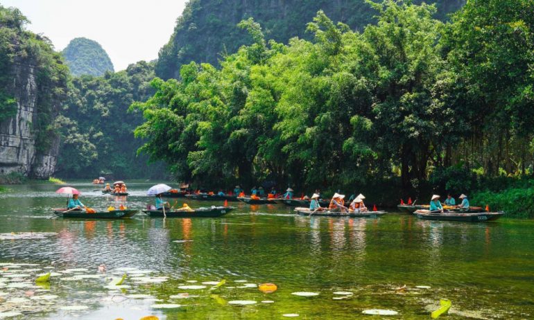 Many guests on bamboo boats in Tam Coc Ninh Binh wearing conical hats.