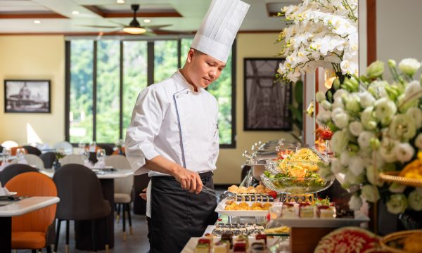 A chef holding a tong in front of a buffet station.