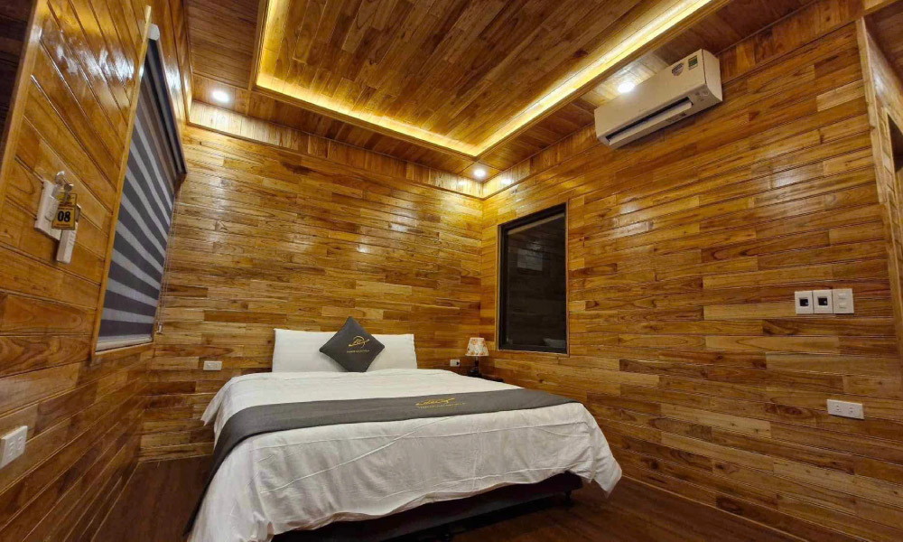 A wooden room with a white bed in the middle and an air conditioner.