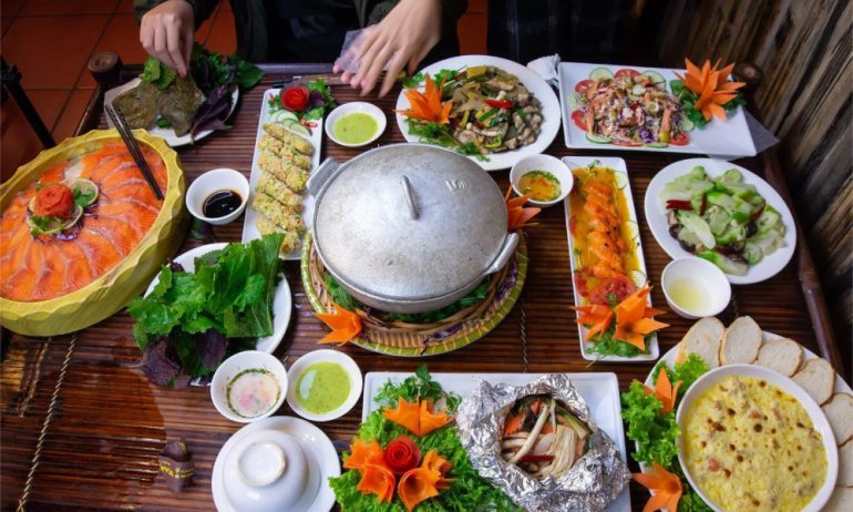 Table with a big pot in the middle and many plates of Vietnamese food.