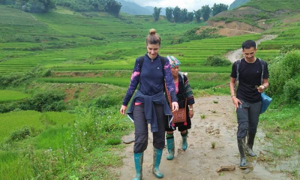 Two people trekking with an ethnic woman among the rice field.