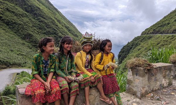 Four ethnic young girls sitting on a block.