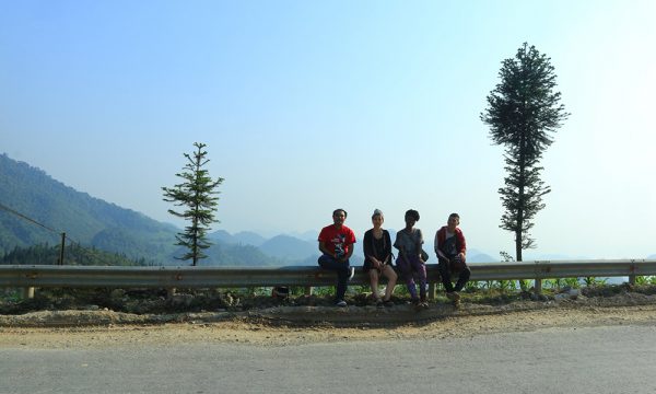 Four people sitting on a road side in Ha Giang.