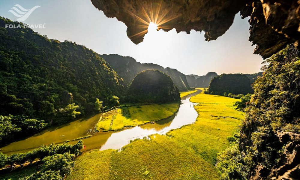 View from a cave looking out to mountains and rice fields.