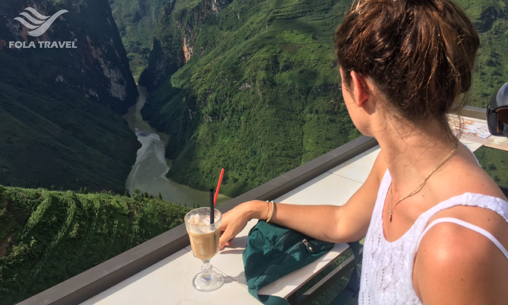 A woman with a drink looking out to Nho Que river.