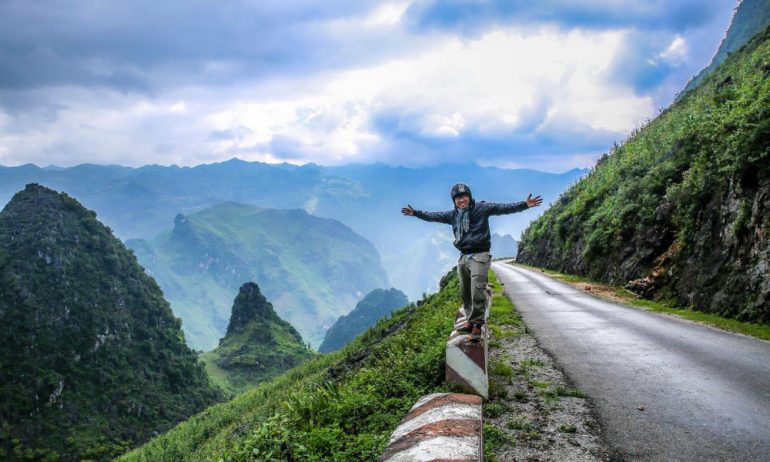 A man standing on Ha Giang Loop with backdround of mountains.