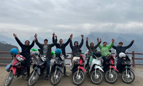 A group of people on motorbikes in front of Ha Giang mountains.