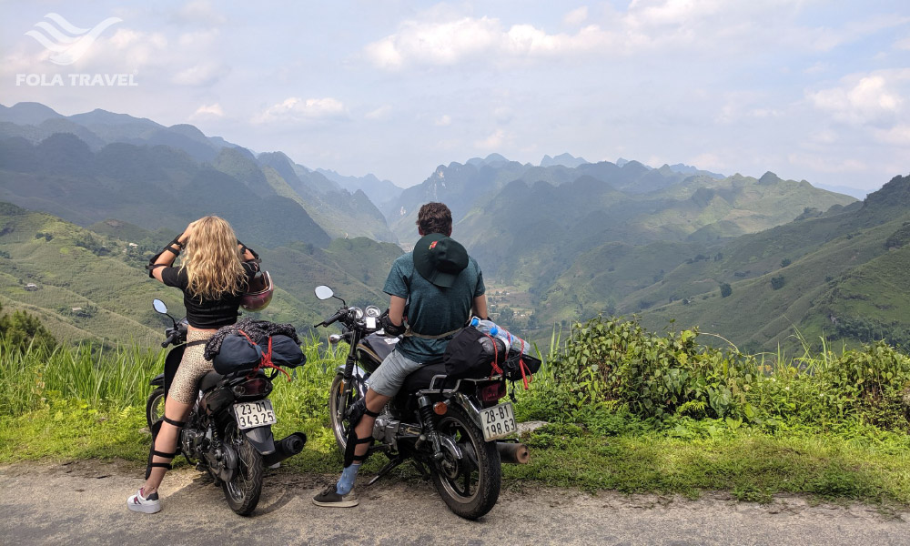 Two people on motorbikes looking out to Ha Giang view.