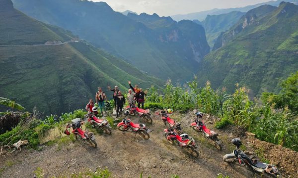 People and motorbikes in front of Nho Que mountains view.