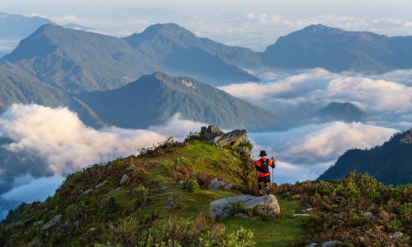 A person hiking on top of a mountain looking out to other Sapa mountains.