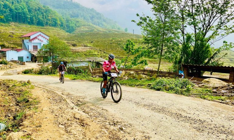 Two people cycling on the dirt trail in Sapa village.