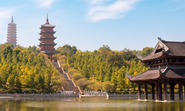 The Thien Mu pagoda panorama with forests surrounding and a lake in front of it.