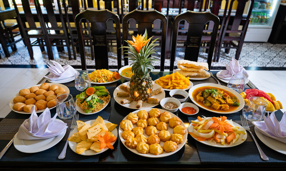 A table with twelve plates of Vietnamese food.