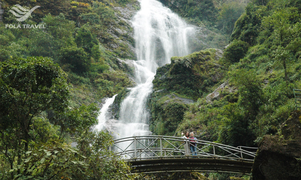 Two people on a bridge under Silver waterfall.