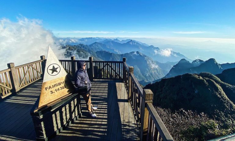 A person standing on Fansipan viewpoint looking out to the mountains.