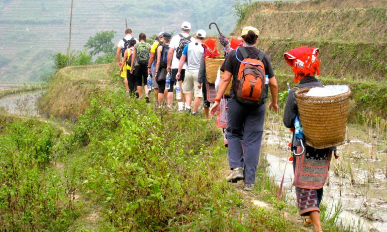 Tourists walking with locals on a terraced field.