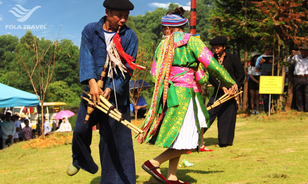 Two people playing khen and dancing in a festival.