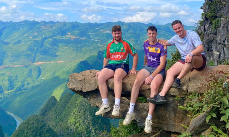 Three people on the skywalk looking out to Ha Giang mountains.