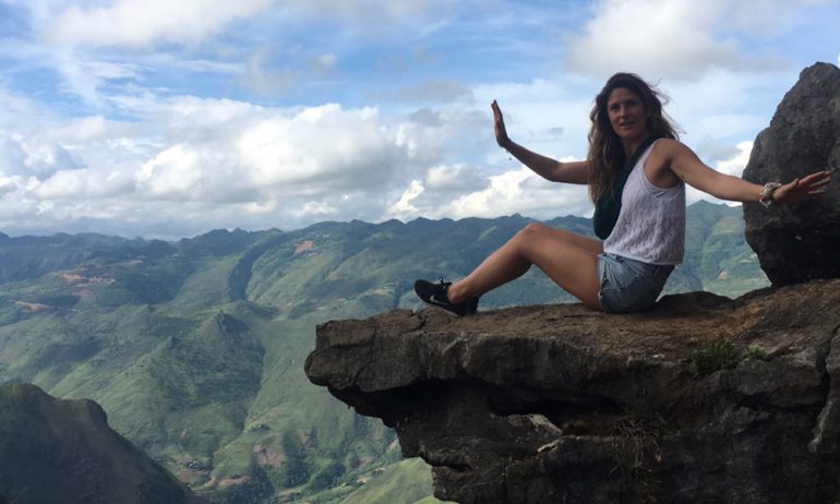 A women sitting on a rock on the right with view of Ha Giang moutains.