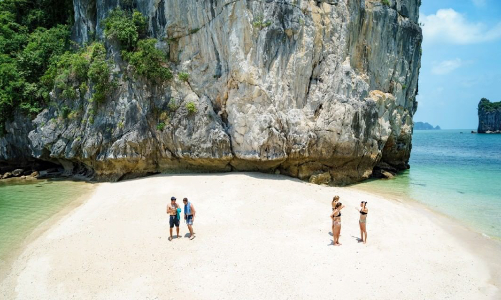 Four people on a sand beach in Lan Ha Bay.