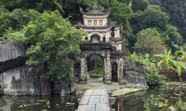 The gate of Bich Dong Pagoda in front of a pond.
